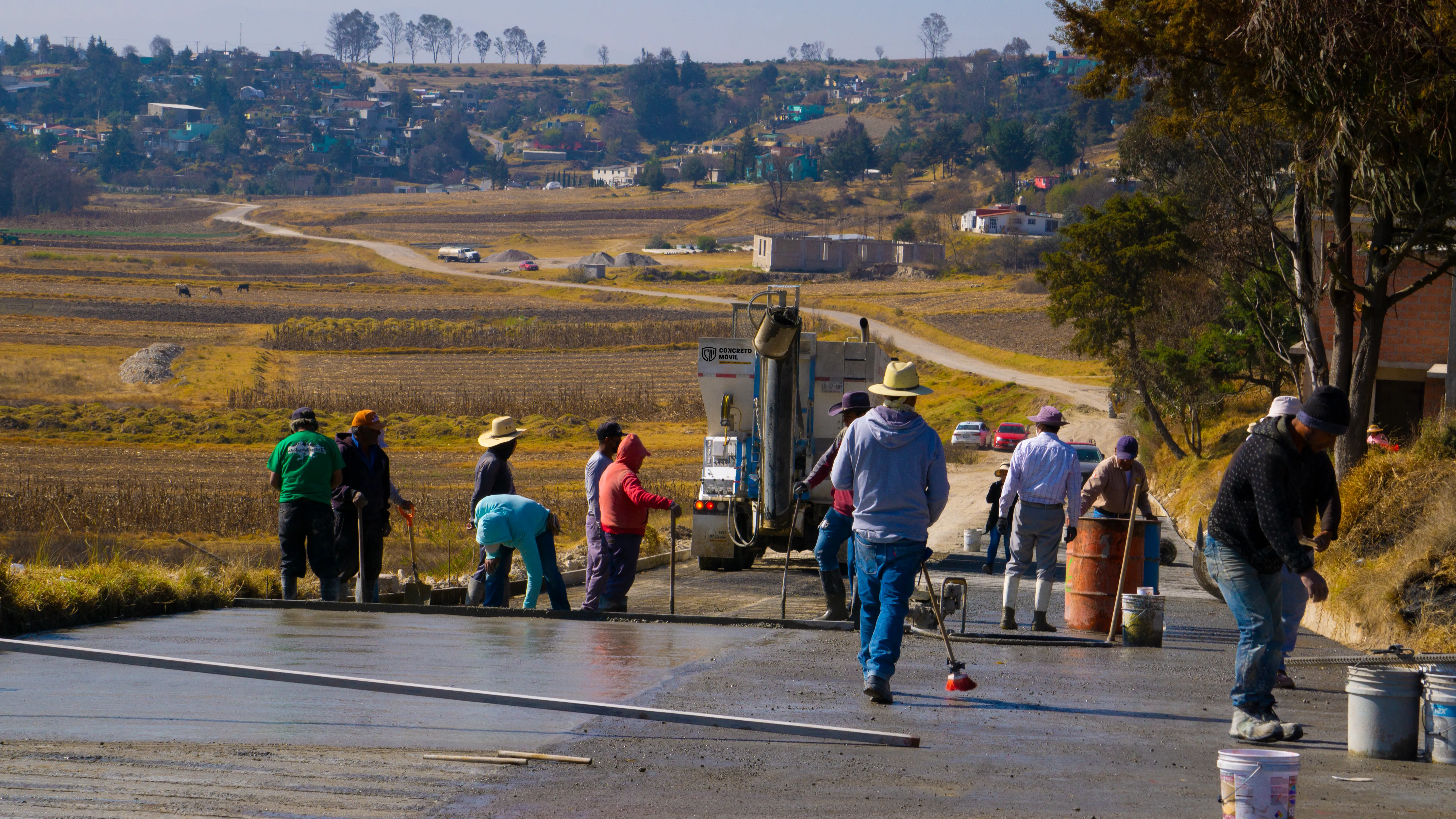 Trabajadores realizando el colado de pavimento mientras se previenen errores al operar una planta de concreto móvil en el sitio.
