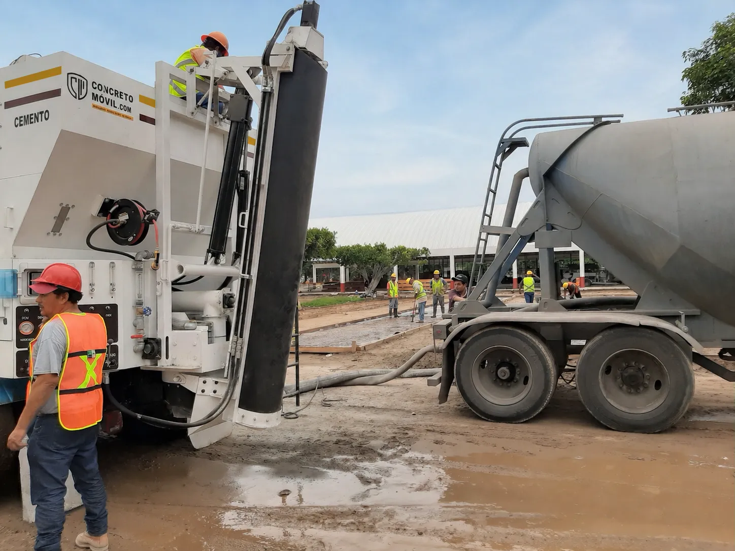 Operarios trabajando junto a maquinaria pesada durante la venta de concretera móvil en un terreno de construcción.